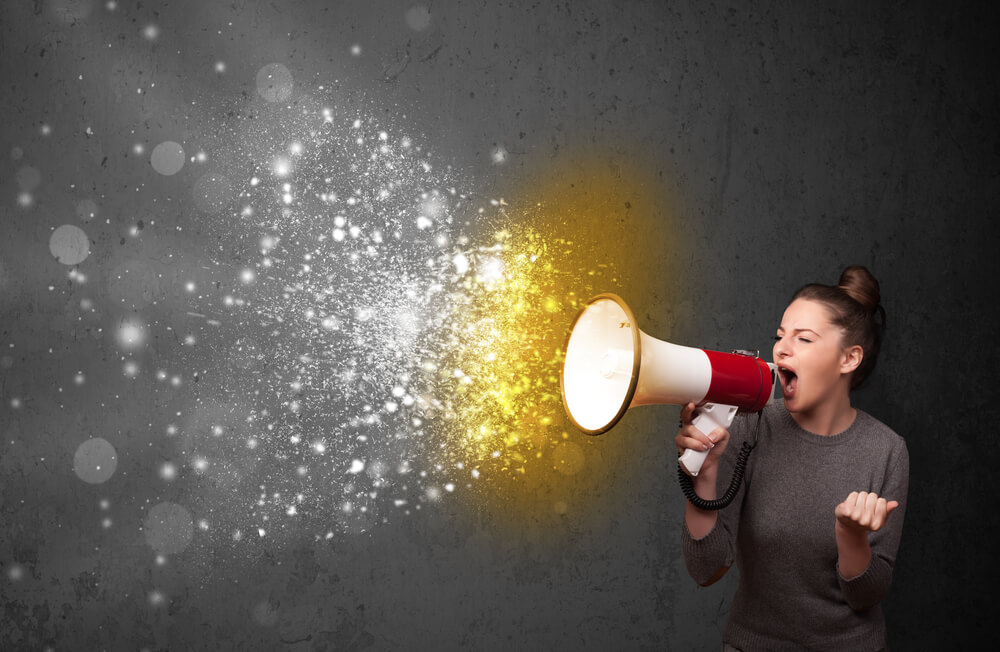 Woman shouting into megaphone and glowing energy particles explode concept